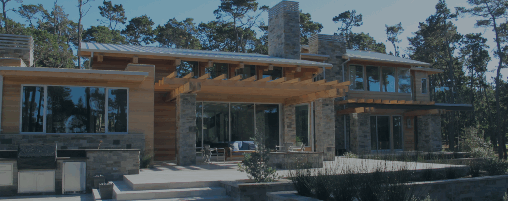 Luxury home surrounded by trees, featuring Shakertown® natural cedar panel siding, large glass windows, stone accents, and wooden pergolas banner header